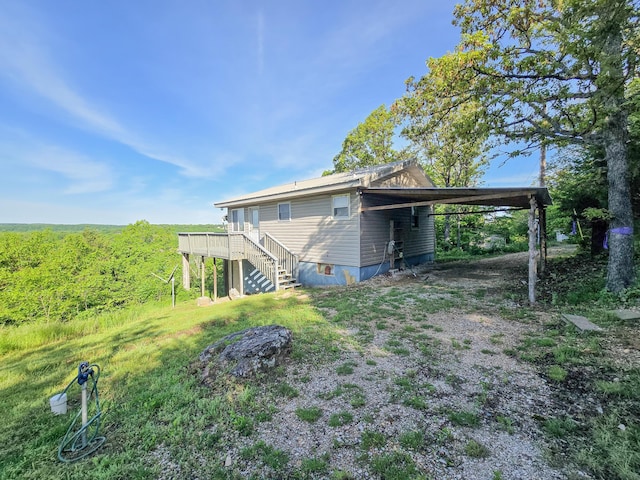 25454 Tulip Pl, Urbana, MO 65767 - back of house featuring driveway, stairway, a wooden deck, and an attached carport