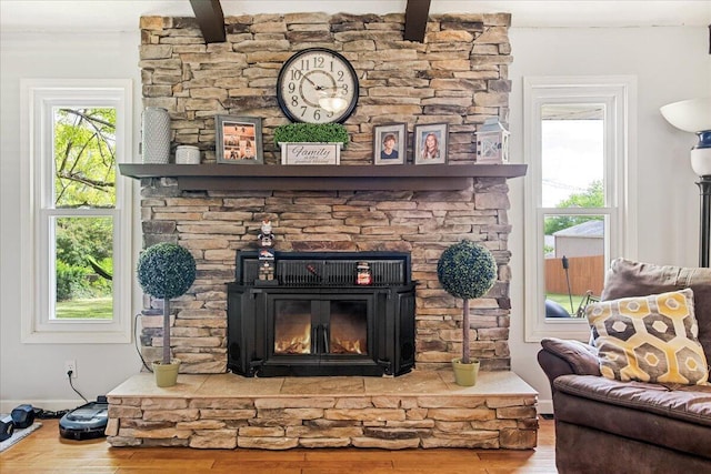 interior space featuring a fireplace, beamed ceiling, baseboards, and wood finished floors