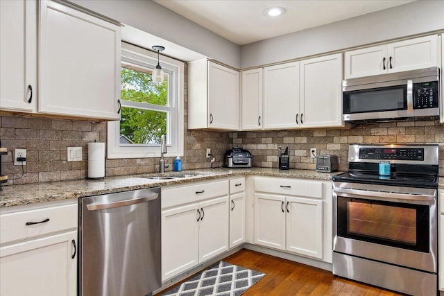 kitchen with a sink, wood finished floors, white cabinetry, and appliances with stainless steel finishes