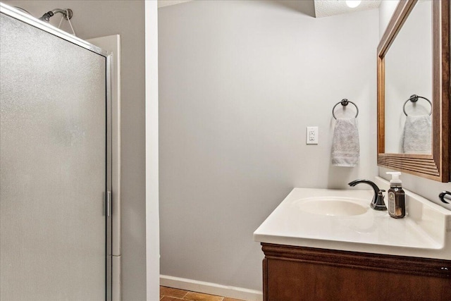 bathroom with a stall shower, baseboards, and vanity