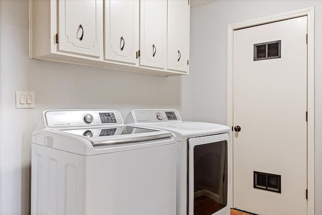 laundry area with washing machine and dryer, cabinet space, and visible vents