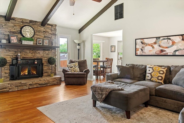 living room with beam ceiling, visible vents, wood finished floors, and a ceiling fan