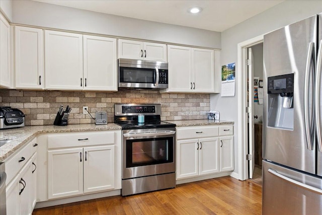 kitchen featuring light wood finished floors, white cabinetry, appliances with stainless steel finishes, tasteful backsplash, and recessed lighting