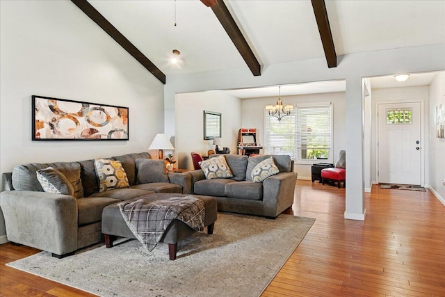 living area with baseboards, lofted ceiling with beams, a chandelier, and hardwood / wood-style flooring