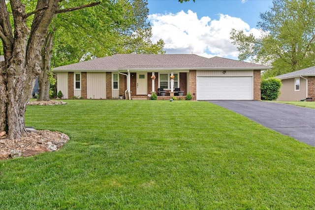 single story home with covered porch, an attached garage, a front lawn, brick siding, and driveway