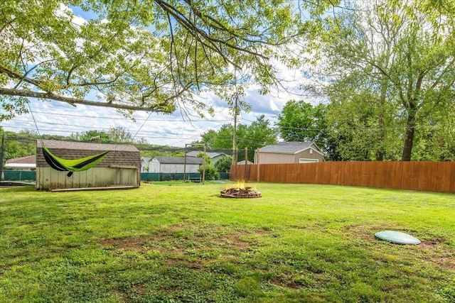 view of yard with a fenced backyard, an outdoor fire pit, a storage shed, and an outdoor structure