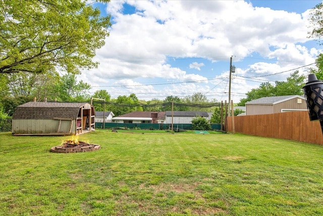 view of yard featuring a fire pit, an outdoor structure, fence, and a shed