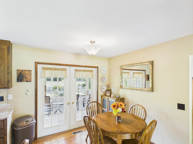 dining space with light wood-style floors, french doors, and visible vents