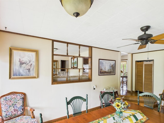 dining area featuring baseboards, ornamental molding, ceiling fan, and wood finished floors