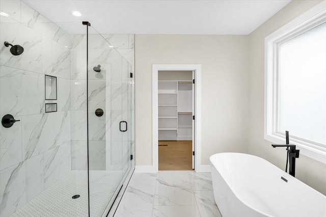 full bathroom featuring marble finish floors, a stall shower, a freestanding tub, a spacious closet, and baseboards