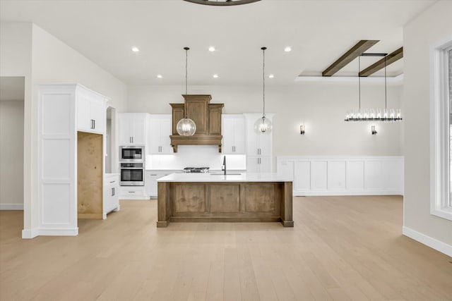 kitchen featuring appliances with stainless steel finishes, light wood finished floors, premium range hood, light countertops, and white cabinetry