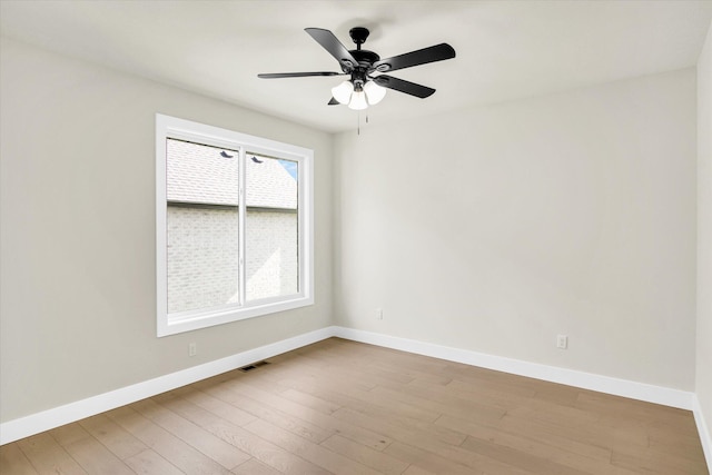 spare room with baseboards, wood finished floors, and a ceiling fan