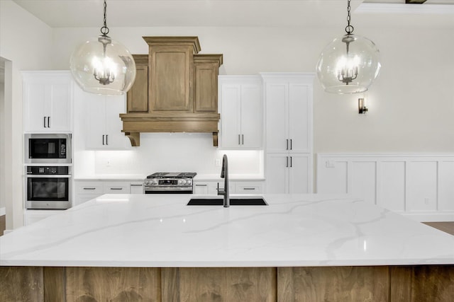 kitchen featuring stainless steel appliances, a sink, a large island, decorative backsplash, and decorative light fixtures