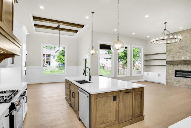 kitchen featuring a sink, stainless steel appliances, light wood-style floors, plenty of natural light, and wainscoting