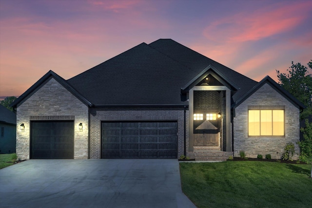 traditional home featuring concrete driveway, an attached garage, stone siding, and a lawn