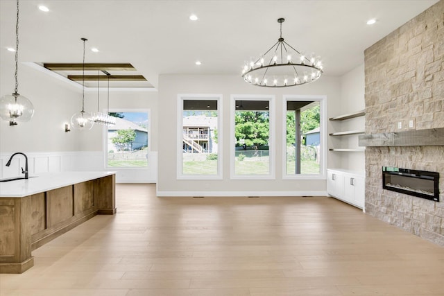 unfurnished living room featuring a chandelier, a sink, light wood-type flooring, recessed lighting, and built in shelves