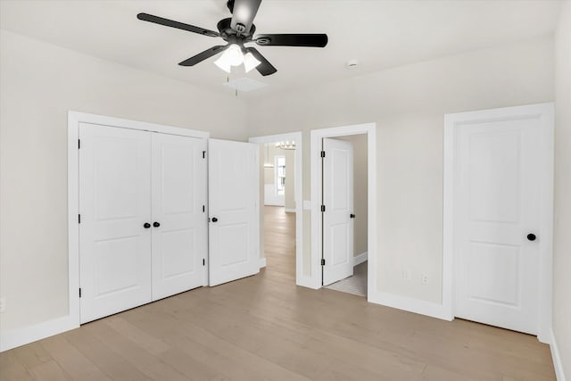 unfurnished bedroom featuring light wood-style floors, baseboards, a chandelier, and a closet