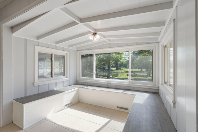 unfurnished sunroom featuring lofted ceiling with beams, visible vents, and tile patterned floors