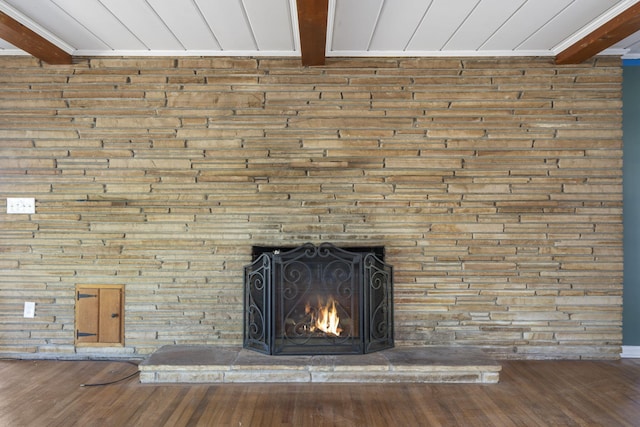 interior details featuring ornamental molding, beamed ceiling, wood finished floors, and a stone fireplace