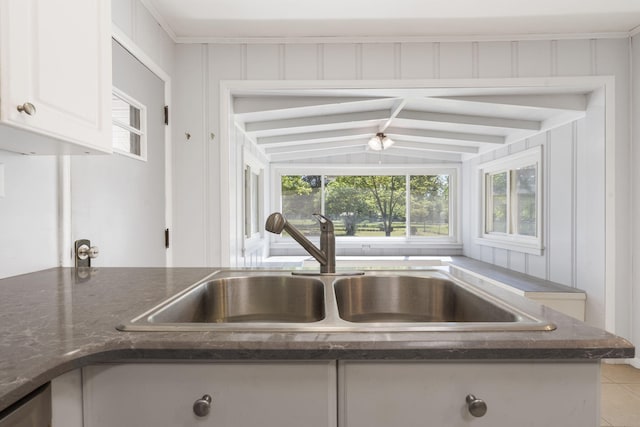 kitchen with white cabinetry, a healthy amount of sunlight, dark stone counters, and a sink