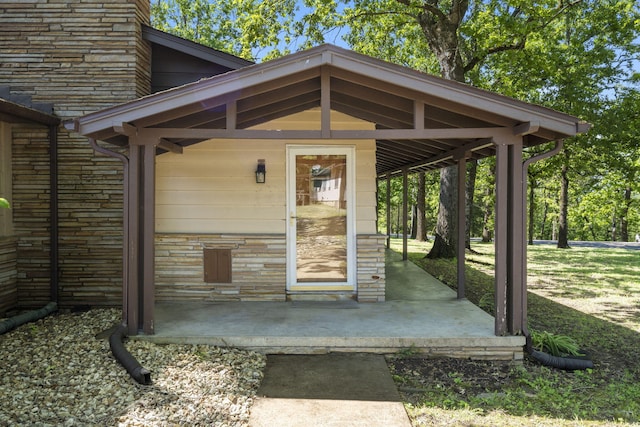 entrance to property featuring stone siding, a porch, and a chimney