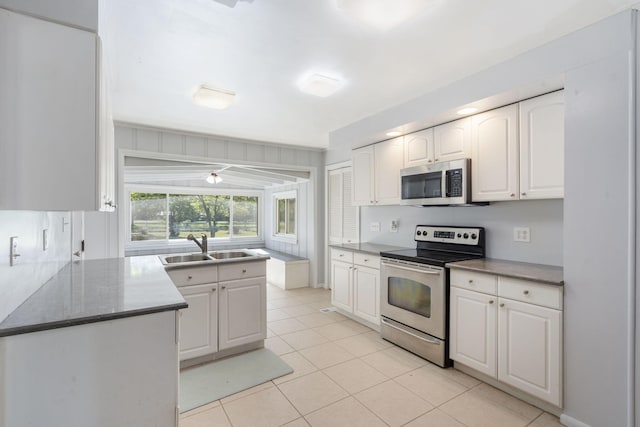 kitchen with light tile patterned flooring, white cabinets, appliances with stainless steel finishes, and a sink