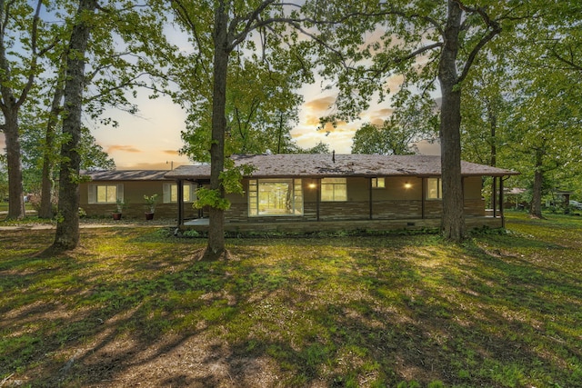 back of house at dusk featuring a yard