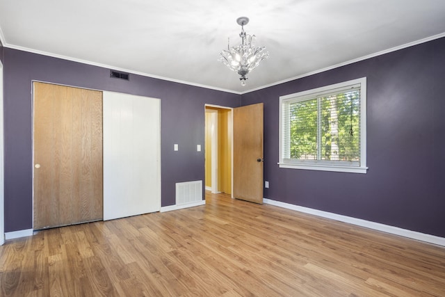 unfurnished bedroom featuring a notable chandelier, baseboards, visible vents, and wood finished floors
