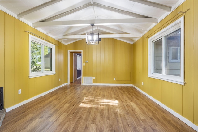 unfurnished room featuring baseboards, visible vents, wood finished floors, and lofted ceiling with beams