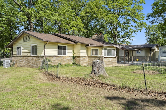 ranch-style home featuring fence, a chimney, a front lawn, and stone siding