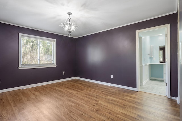 empty room featuring a chandelier, wood finished floors, baseboards, and ornamental molding