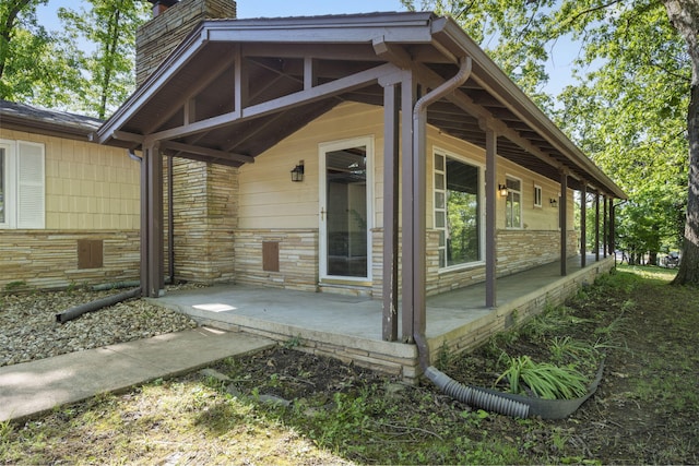exterior space with stone siding, a patio area, and a chimney