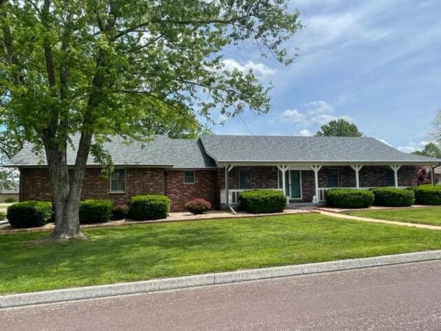 ranch-style house with a shingled roof, a front lawn, and brick siding