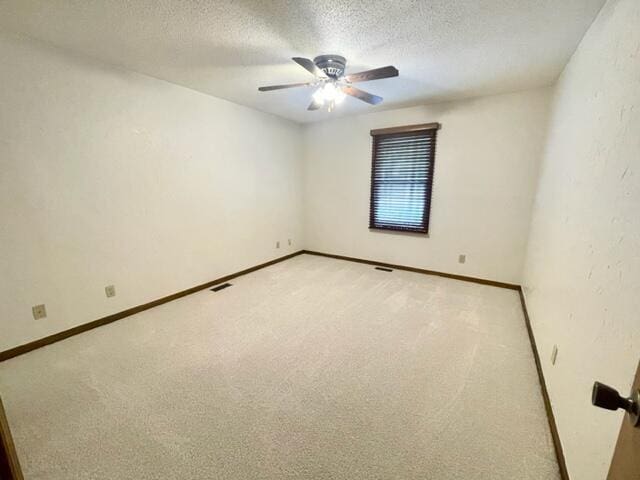 unfurnished room featuring light colored carpet, a textured ceiling, baseboards, and a ceiling fan