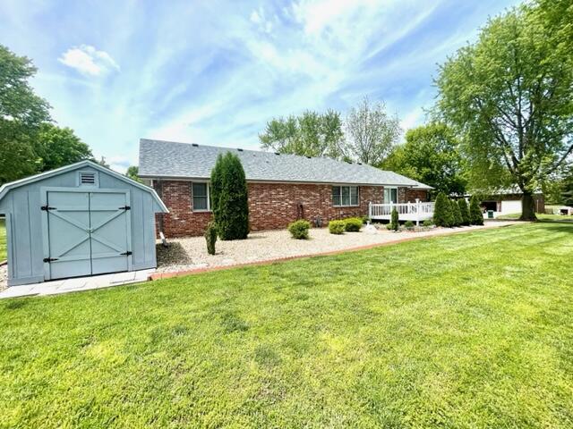 back of house featuring a yard, an outdoor structure, and a shed