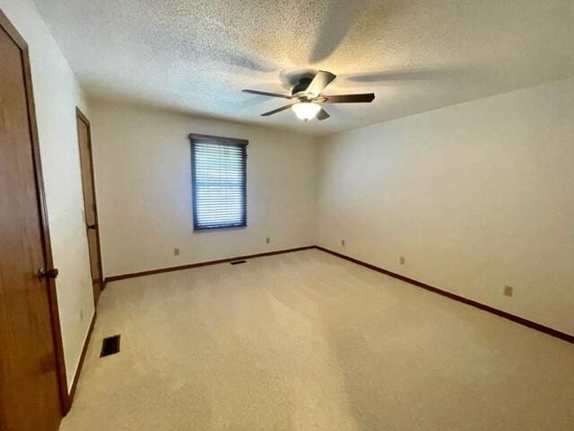 spare room featuring ceiling fan, a textured ceiling, baseboards, and visible vents