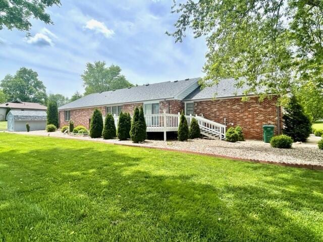 view of front of property with a front lawn, brick siding, and a wooden deck