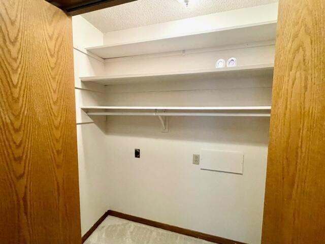 laundry room featuring baseboards, carpet flooring, and a textured ceiling