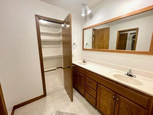 full bath featuring tile patterned floors, double vanity, a spacious closet, and a sink