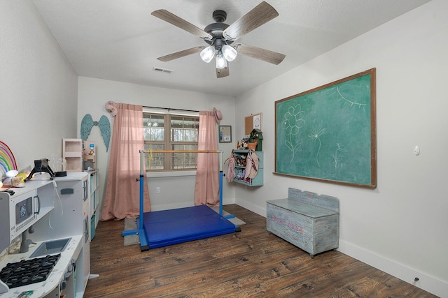 exercise area with baseboards, wood finished floors, a ceiling fan, and visible vents