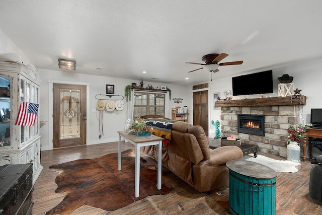 living area featuring ceiling fan, recessed lighting, a stone fireplace, and wood finished floors