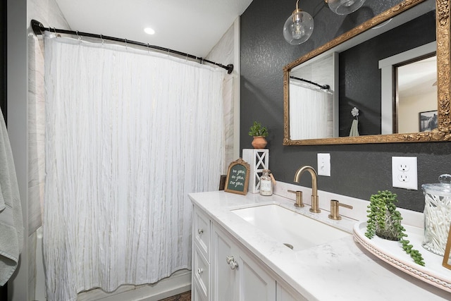 full bath with vanity and a textured wall