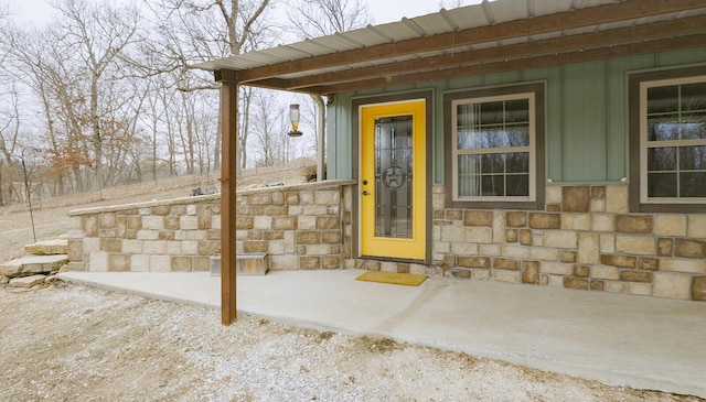 view of exterior entry featuring stone siding and board and batten siding