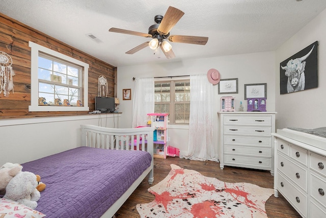 bedroom with a textured ceiling, a ceiling fan, visible vents, and dark wood finished floors
