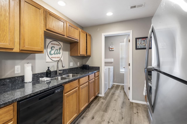 kitchen featuring freestanding refrigerator, dishwasher, visible vents, a sink, and washing machine and clothes dryer