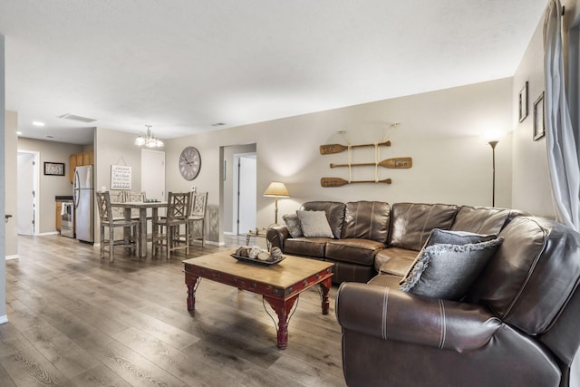 living room with baseboards, an inviting chandelier, visible vents, and wood finished floors