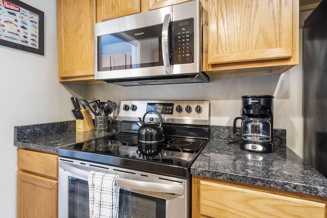 kitchen featuring dark countertops, stainless steel appliances, and light brown cabinets