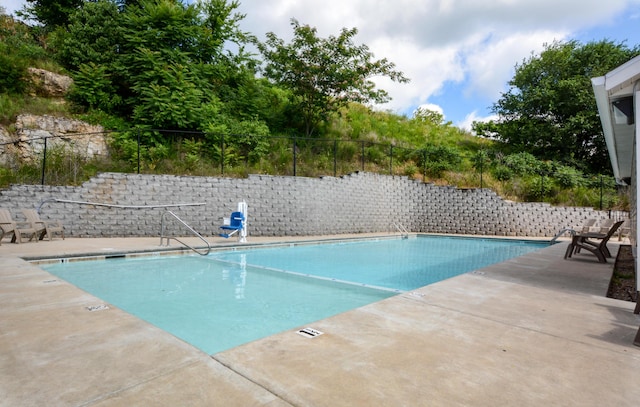 community pool with a patio area and fence