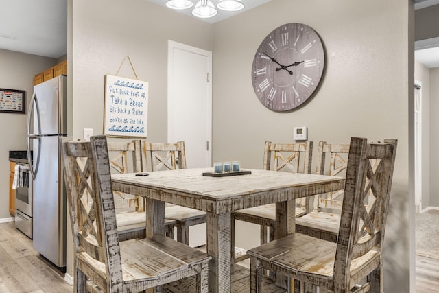 dining space with baseboards, a notable chandelier, light wood-style floors, and visible vents