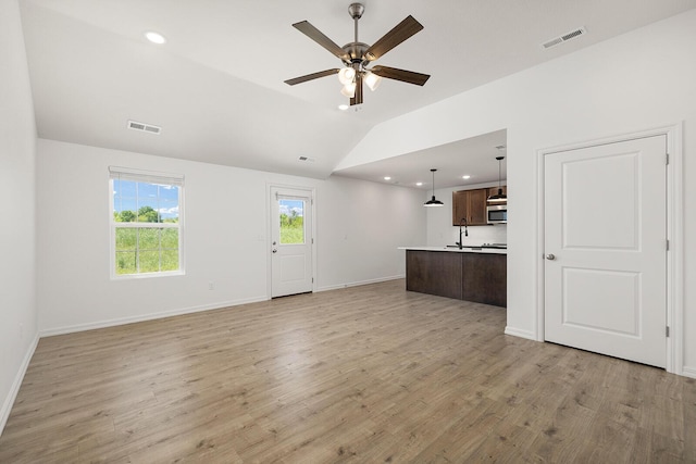 unfurnished living room with vaulted ceiling, a ceiling fan, visible vents, and light wood-style floors